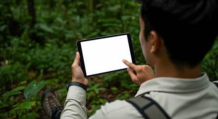 Man using tablet in lush green jungle exploring nature technology travel adventure backpacking wilderness digital nomad remote work