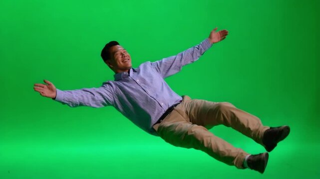 Levitating Joy: A man floats mid-air against a vibrant green backdrop, his arms outstretched and a look of pure joy on his face, symbolizing freedom and boundless possibilities.