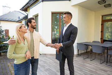 Family meeting realtor for house deal in front of modern property