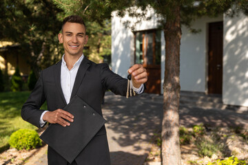 Real estate agent holding keys and clipboard in front of modern house for property