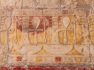 Ancient egyptian ankh crosses and was scepters carved on a stone wall