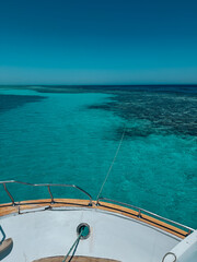 Obraz premium Boat sailing on turquoise water near coral reef in tropical sea