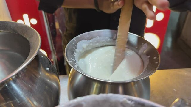 closeup of man making lassi traditionally by hand mixing the yogard, sugar and ice