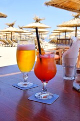 Two glasses of cool cocktail and beer on the table at the beach bar.
