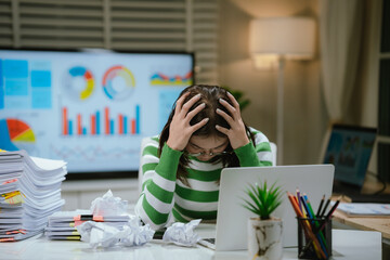A stressed woman works late at a cluttered desk, surrounded by papers and charts, overwhelmed with...