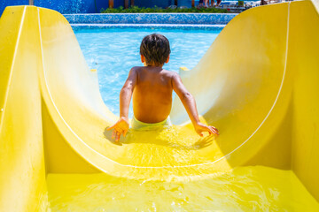 Child sliding down yellow waterslide in swimming pool