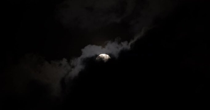 Black clouds passing away revealing the white moon