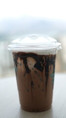 iced chocolate drink with milk foam, refreshing sweet drink in plastic glass.