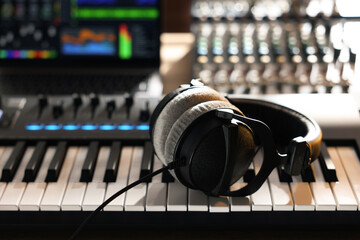 MIDI keyboard with headphones, dj mixer and laptop on table, closeup