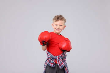 Little boy with boxing gloves on gray background