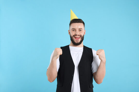 Happy Birthday. Handsome man with party hat on light blue background, space for text