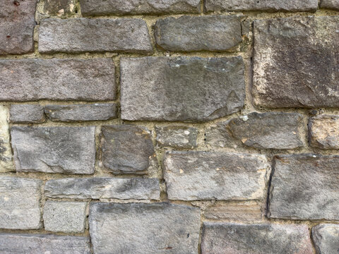 Rustic Charm of a Weathered Stone Wall in Natural Light: Perfect Architectural Background