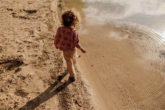 Children on a sandy lakeshore under soft golden sunlight