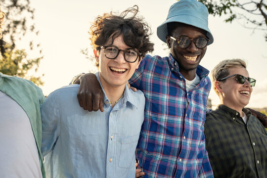 An energetic, diverse group of young friends laughing and having fun together outdoors. A multiethnic team celebrating friendship and community with authentic joy and positive expressions. - Powered by Adobe