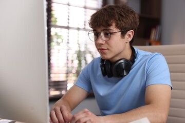 Teenage student with headphones using computer while studying at home