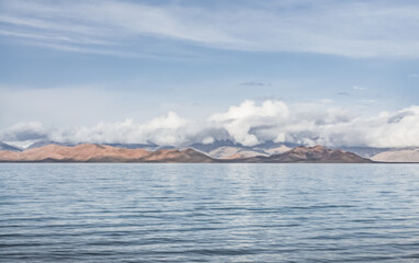 Panorama landscape of Lake Karakul in the Pamir mountains in the Tien Shan against the background of high snowy rocky peaks with clouds, morning panorama of the lake for the background