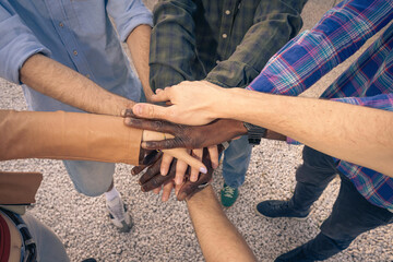 Top down view of a diverse group stacking their hands together. Concept of teamwork, unity,...