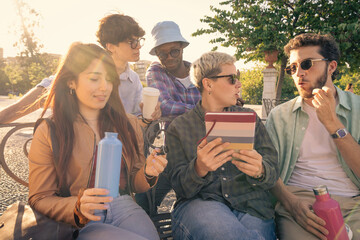 A diverse group of young students or freelancers collaborating outdoors on a laptop. Modern team...