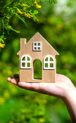 A girl holds the symbol of a house against a blooming acacia tree
