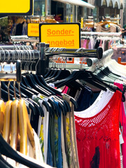 Sommerkleider in leuchtenden Farben auf einem Kleiderständer im Straßenverkauf in Wuppertal,...