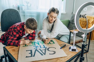 Brother and sister creating an environmental protest sign for social media