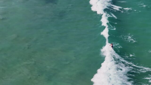 UHD Drone Video - Aerial View of Surfers catching the waves at Wanda Beach in Cronulla on a sunny day with crystal clear water in Sydney, NSW, Australia.