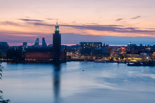 Panoramic view of Stockholm cityscape at sunset with illuminated buildings and Lake Malaren.
