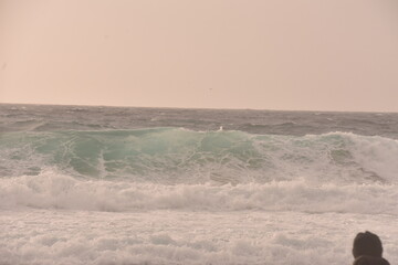 Powerful ocean waves crashing under a soft pastel-toned sky during sunset. The golden light of the...