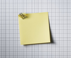 Blank squared paper sheet clipped with metal binder against white background in minimalist office stationery flat lay

