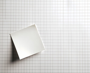 Blank squared paper sheet clipped with metal binder against white background in minimalist office stationery flat lay

