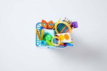 Flat lay of school and office supplies. A basket full of various stationery for study and creativity on a white background © photoguns