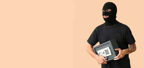 Male thief with stolen safe box on beige background with space for text