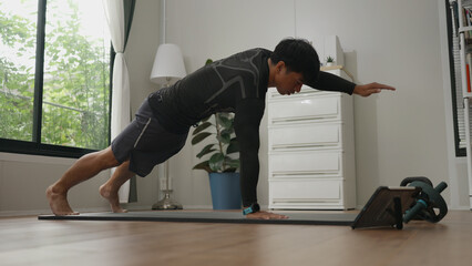 Asian man is performing push-ups at home as part of his strength and fitness routine.