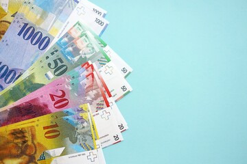 Swiss franc banknotes on blue background. The current francs money bills lies in big amount