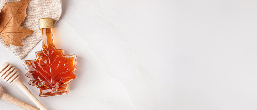 Bottle of tasty maple syrup on grey background