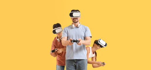 Father and his children with VR glasses playing video game on yellow background