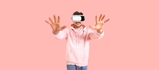 Young bearded man using VR glasses on pink background
