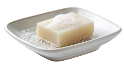 A bar of soap with bubbles sitting in a white soap dish on a black background in a studio shot view