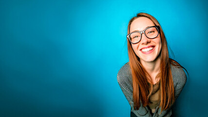 junge Frau mit Brille lehnt nach vorne und grinst