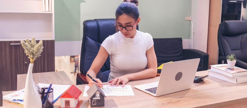 Banner Asian Female freelance using laptop at home office desk. Banner Woman reading financial graph chart Planning analyzing marketing data. Asian female people working office firm with copy space