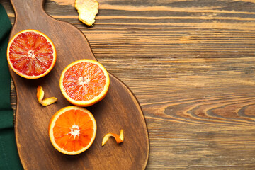 Board with tasty blood oranges on wooden background