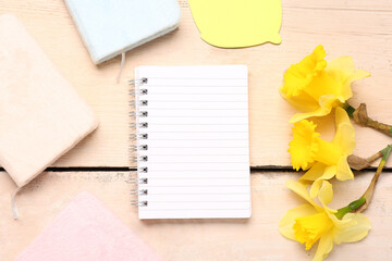 Composition with notebooks and beautiful narcissus flowers on wooden table