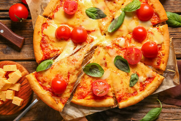 Baking paper with tasty pizza margarita on wooden table