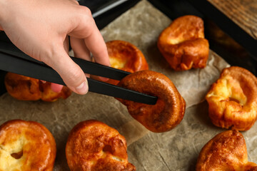 Woman taking tasty Yorkshire pudding from baking tray