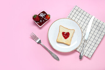 Plate with toast, sweet strawberry jam and cutlery on pink background