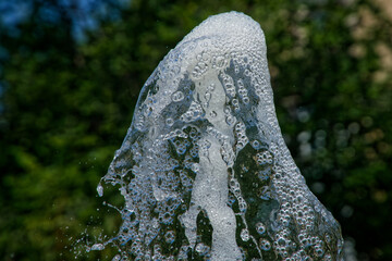 Dynamic shot of water splashing with greenery in the background, illustrating freshness and outdoor...