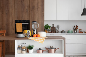 Blender, toaster, juicer, oranges and cooking pot on wooden table in kitchen