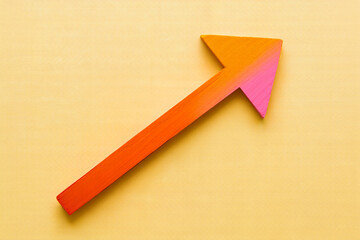 An arrow pointing upwards with orange and pink gradient on a yellow background