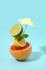 Different citrus fruits with decorative umbrella on blue background