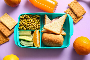 Lunchbox with delicious food and bottle of juice on lilac background